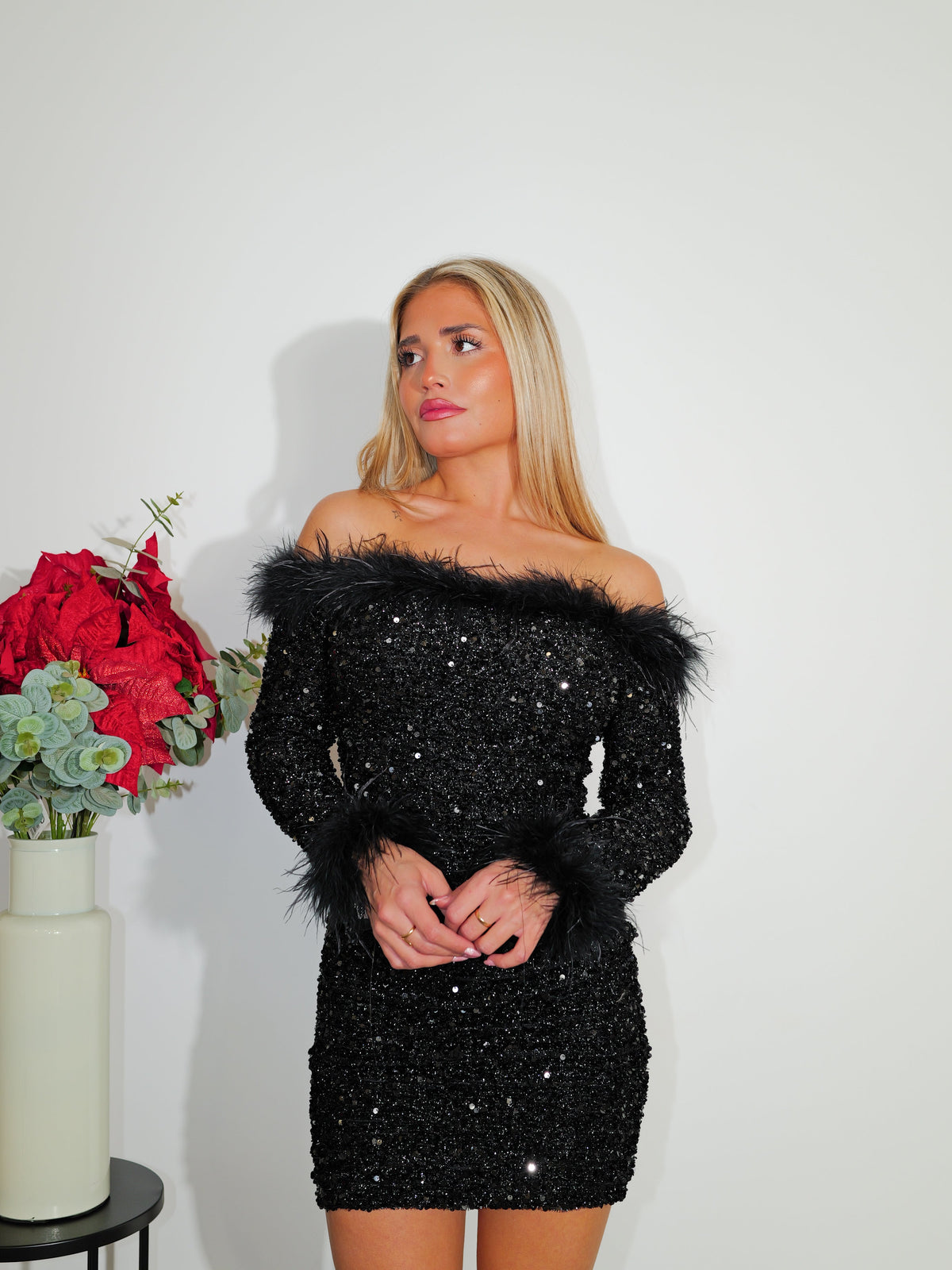 Vestido preto com decote bardot, brilho e penas